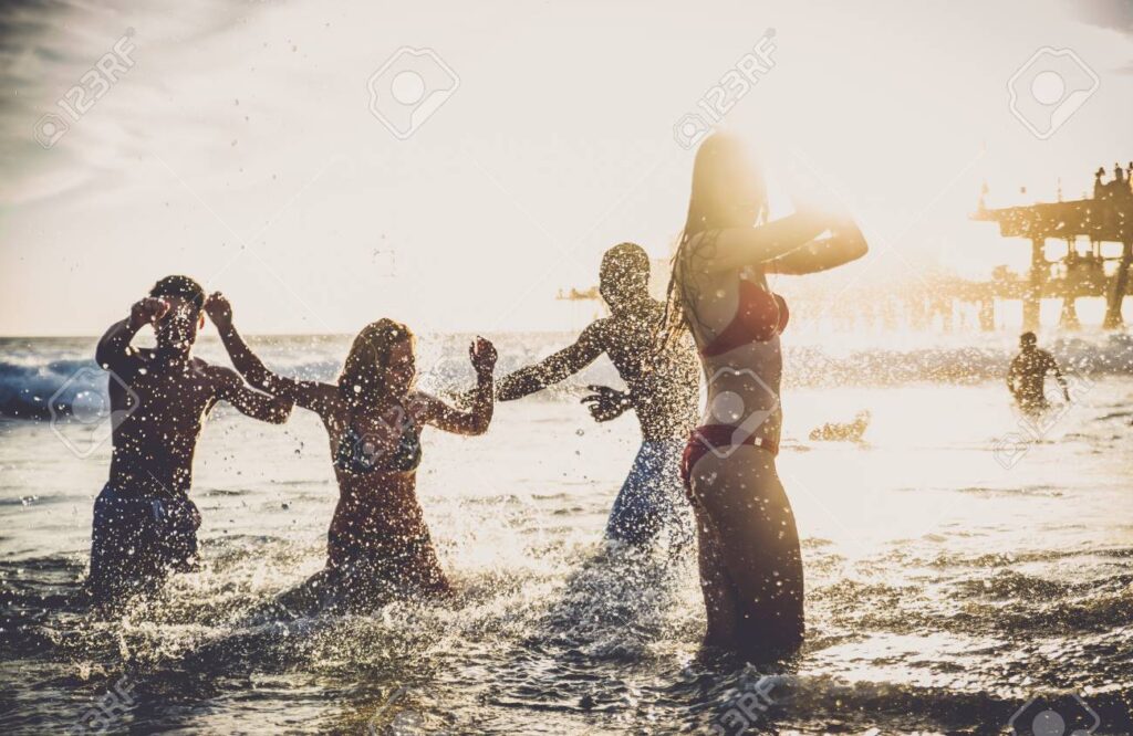 102313176 Group Of Friends Splashing Water While Swimming In The Sea Multi Ethic Group Of People Having Fun